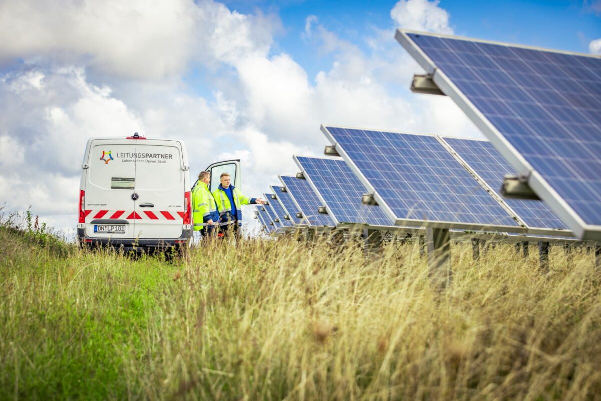 Zwei Monteure zwischen Kastenwagen von Leitungspartner und Solaranlagen